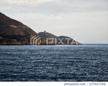Historic tower atop rocky seaside cliffs, Calm waters beside ancient rugged coastal landscape with tower Historic tower atop rocky seaside cliffs, Calm waters beside ancient rugged coastal landscape with tower 137027108