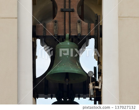 Historic bronze bell in tower, Patinated bronze bell beneath arched sky backdrop in village square Historic bronze bell in tower, Patinated bronze bell beneath arched sky backdrop in village square 137027132