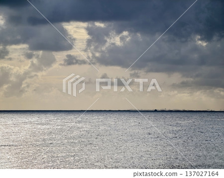 Over peaceful sea with vessels, Overcast sky above serene sea featuring faraway boats with soft illumination 137027164