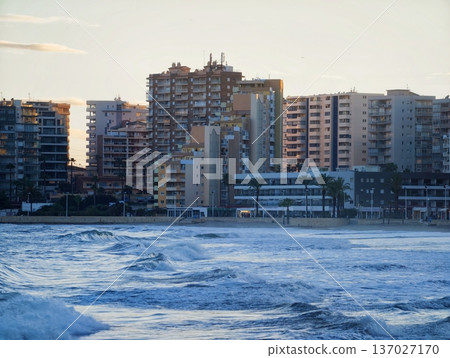 Twilight ocean scene, City skyline meets ocean waves, Dramatic coast with surfers and city backdrop Twilight ocean scene, City skyline meets ocean waves, Dramatic coast with surfers and city backdrop 137027170