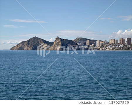 Magnificent cliffside scenery showcasing bright structures and serene aqua waters under radiant sky Magnificent cliffside scenery showcasing bright structures and serene aqua waters under radiant sky 137027229