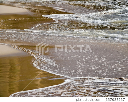 Serene shoreline with gentle ripples, Quiet seaside landscape showing smooth reflections and calming waves 137027237