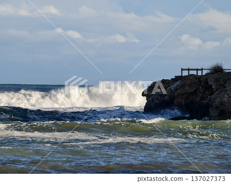 Vigorous ocean waves smash against constructed rock formations creating striking storm environment 137027373