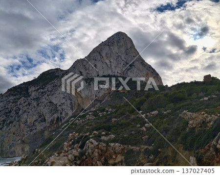 Mountain summit amid storm clouds, Foreboding mountain crest surrounded by turbulent dark clouds Mountain summit amid storm clouds, Foreboding mountain crest surrounded by turbulent dark clouds 137027405
