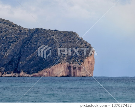 Stunning seaside rocky promontory, Elevated crag overlooking peaceful waters with visible sediment layers 137027432