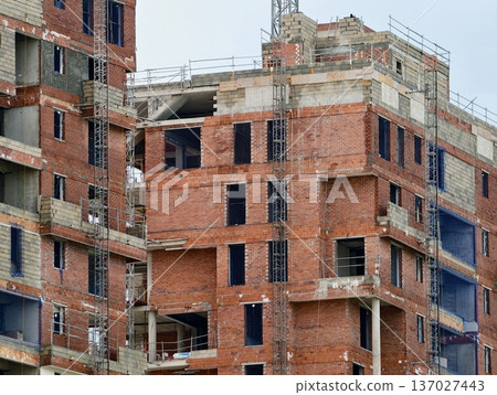 An unfinished red brick edifice showcasing open window spaces and overcast weather backdrop 137027443