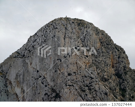 Rugged peak under cloudy sky, Silent elevated mountain with shadowed ledges and muted illumination Rugged peak under cloudy sky, Silent elevated mountain with shadowed ledges and muted illumination 137027444