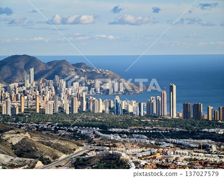 Skyline captures nature, Vivid image of city buildings set against vast mountain range and open sea 137027579
