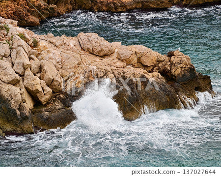 Dynamic sea crashes vigorously, Powerful ocean surf collides with rugged cliff formations vividly 137027644
