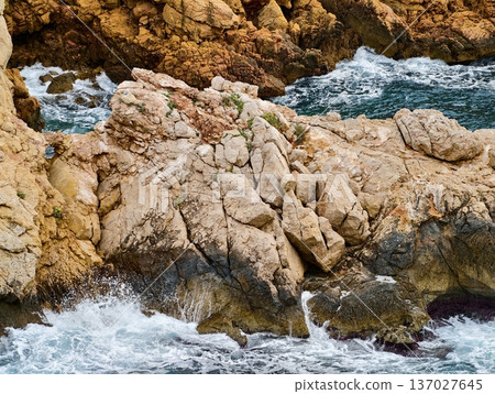 Stormy sea surge, Rough ocean strikes jagged coast, Chaotic waves collide with rugged shoreline rocks 137027645