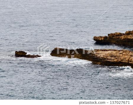 Foamy surf with broken reef stones, Wet textured stones amid breaking waves and coastal shallow reefs 137027671