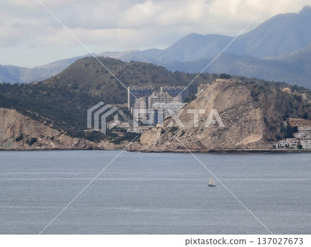 Quiet seashore with distant village, Calm seaside scene with rugged cliffs and modern structures Quiet seashore with distant village, Calm seaside scene with rugged cliffs and modern structures 137027673