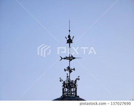 Refined metallic weather vane featuring detailed craftsmanship and modern design elements in cityscape setting 137027690