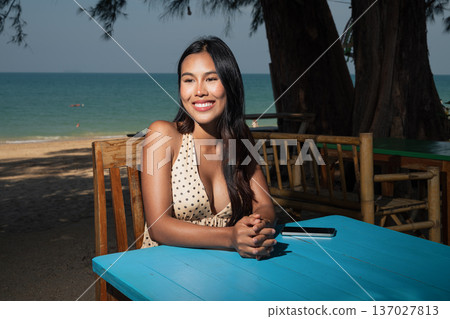 Smiling Woman Sitting at Beachside Cafe Table Smiling Woman Sitting at Beachside Cafe Table 137027813