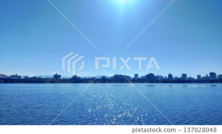 The blue winter sky and the sparkling river surface reflecting the sun The blue winter sky and the sparkling river surface reflecting the sun 137028048