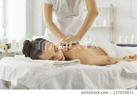 Wellness spa therapist giving relaxing back massage on table with soft towels 137028651