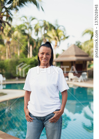 Smiling beautiful older Scandinavian tourist woman standing near swimming pool during holiday 137028948