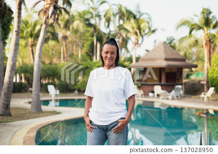Smiling beautiful older Scandinavian tourist woman standing near swimming pool during holiday 137028950