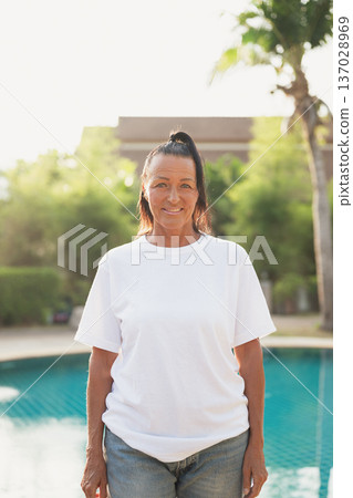 Smiling beautiful older Scandinavian tourist woman standing near swimming pool during holiday Smiling beautiful older Scandinavian tourist woman standing near swimming pool during holiday 137028969