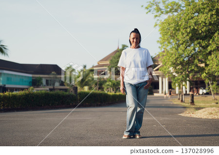Smiling Mature Scandinavian Tourist Woman Walking Outdoors on Summer Holiday Smiling Mature Scandinavian Tourist Woman Walking Outdoors on Summer Holiday 137028996