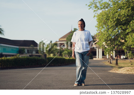Smiling Mature Scandinavian Tourist Woman Walking Outdoors on Summer Holiday Smiling Mature Scandinavian Tourist Woman Walking Outdoors on Summer Holiday 137028997