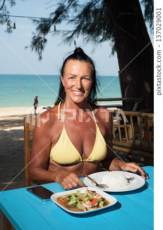 Active senior woman enjoying seafood and rice at seaside restaurant in Thailand cafe restaurant 137029001