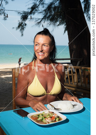 Active senior woman enjoying seafood and rice at seaside restaurant in Thailand cafe restaurant 137029002