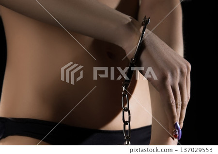Sensual pose of a model with handcuffs in a dark setting Sensual pose of a model with handcuffs in a dark setting 137029553