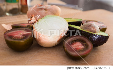 vegetables black tomatoes, avocado and onions on wooden board vegetables black tomatoes, avocado and onions on wooden board 137029897