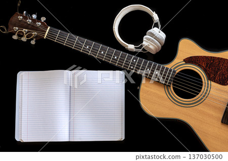 Classical acoustic guitar, headphones and notebook on a black background. Classical acoustic guitar, headphones and notebook on a black background. 137030500
