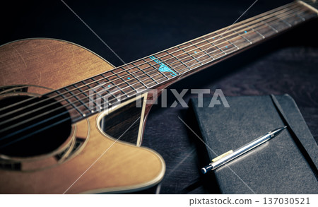 Close-up, acoustic guitar and notepad on a dark background. Close-up, acoustic guitar and notepad on a dark background. 137030521