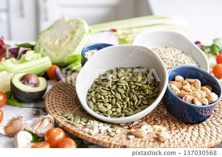 Close-up, a bowl of pumpkin seeds and other healthy foods on the kitchen table. Close-up, a bowl of pumpkin seeds and other healthy foods on the kitchen table. 137030568