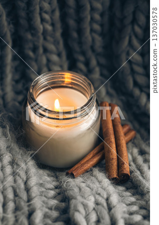 Close-up, candle and cinnamon sticks on the background of a gray knitted element. 137030578