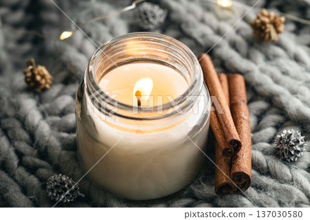 Close-up, candle and cinnamon sticks on the background of a gray knitted element. 137030580