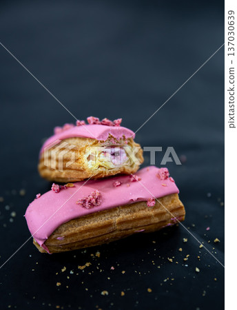 Close-up of a cut berry eclair on a black background. 137030639
