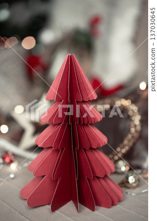 Close-up of a decorative cardboard Christmas tree on a blurred background. Close-up of a decorative cardboard Christmas tree on a blurred background. 137030645