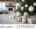 Neutral Christmas scene with knitted baubles and wrapped kraft gifts on white floor, serene palette, natural textures and soft fairy lights create minimalist festive calm 137030655