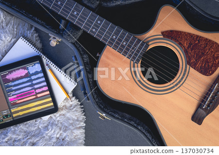Acoustic guitar and digital tablet with a music application, top view. Acoustic guitar and digital tablet with a music application, top view. 137030734