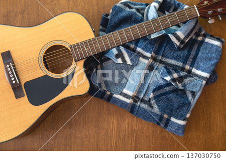 Acoustic guitar and shirt on a wooden background. Acoustic guitar and shirt on a wooden background. 137030750