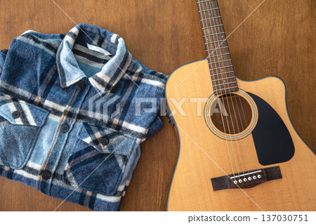 Acoustic guitar and shirt on a wooden background. Acoustic guitar and shirt on a wooden background. 137030751