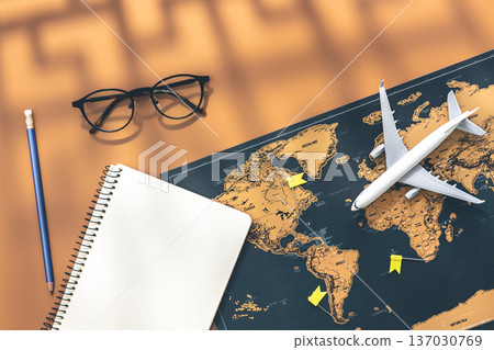 An airplane miniature, notebook and world map on brown background, flat lay. An airplane miniature, notebook and world map on brown background, flat lay. 137030769