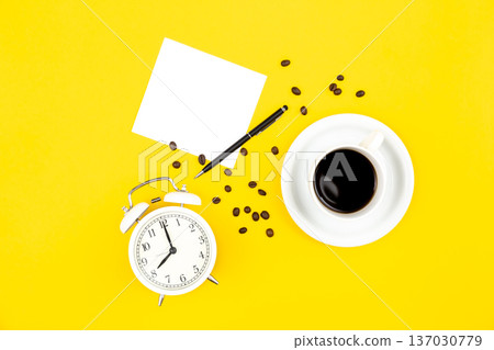 Alarm clock, cup of coffee and paper on a yellow background, flat lay. 137030779