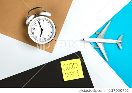 Alarm clock, paper reminder and airplane model on colored paper background. Alarm clock, paper reminder and airplane model on colored paper background. 137030792
