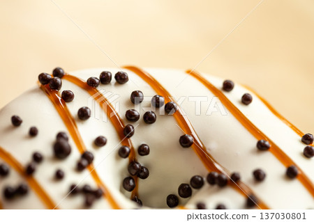 Appetizing donut covered with caramel and crispy balls, macro shot. 137030801