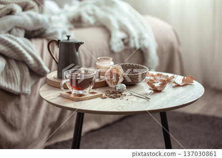 A cup of tea and a teapot on a blurred background of the interior of the room. A cup of tea and a teapot on a blurred background of the interior of the room. 137030861