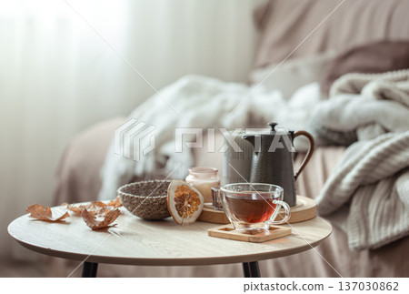 A cup of tea and a teapot on a blurred background of the interior of the room. A cup of tea and a teapot on a blurred background of the interior of the room. 137030862