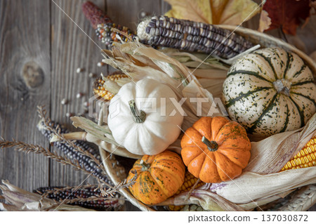 Autumn composition with pumpkins, corn and leaves on a wooden background. Autumn composition with pumpkins, corn and leaves on a wooden background. 137030872