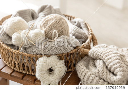 Basket with threads for knitting on a wooden bench in the interior of the room. Basket with threads for knitting on a wooden bench in the interior of the room. 137030939