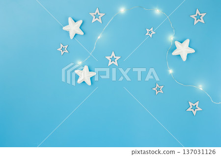 Blue Christmas background with garland and decorative stars, flat lay. Blue Christmas background with garland and decorative stars, flat lay. 137031126