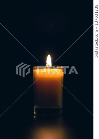 Burning candle on black background with backlight. Memorial Day. Burning candle on black background with backlight. Memorial Day. 137031239